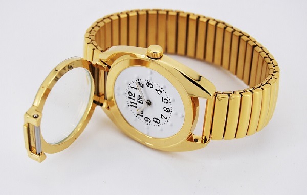 a imagem mostra um relógio dourado posicionado lateralmente em uma mesa com a talpa aberta mostrando o interior do visor do relógio